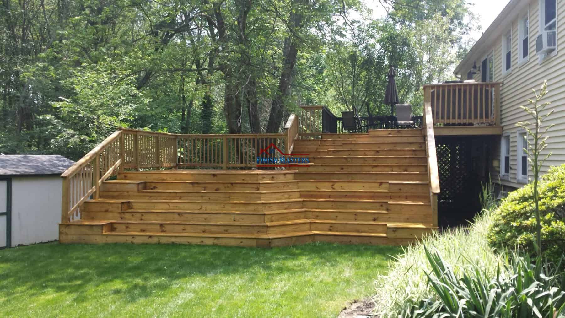 Built wooden deck with stairs and railing in a green backyard setting.