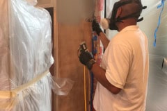 Applying factory smooth spray finish to kitchen cabinets during refinishing project in Groton Massachusetts