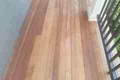 Up of a newly installed hardwood balcony floor with a black metal railing.