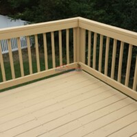 A freshly painted wooden deck with a beige finish, showcasing quality craftsmanship by Finish Masters. Professional deck painting by Finish Masters Construction & Painting.