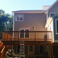 A spacious wooden deck attached to a modern house, showcasing professional construction and painting services by Finish Masters. Image of a newly built wooden deck on a residential home by Finish Masters Construction & Painting.