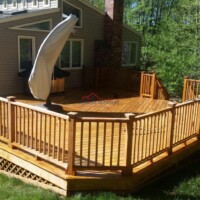 Beautiful outdoor wooden deck with railing and hot tub, perfect for relaxing and entertaining. Deck with wooden railing and hot tub in backyard.