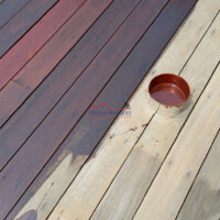 Finish Masters team staining a wooden deck to enhance its appearance and protect it from weather damage. Applying stain to a wooden deck with a paint roller, showing color transformation.