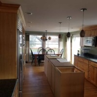 Modern kitchen with wooden cabinets, countertops, and large windows for natural light. Kitchen renovation with custom cabinetry and painting.