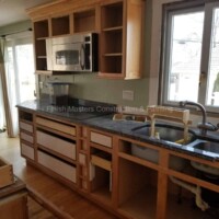 Showcasing a partially installed kitchen with new cabinets and a modern sink. Kitchen cabinet installation in progress.