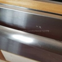 Close-up of a newly installed metal door handle showcasing quality craftsmanship by Finish Masters Construction & Painting. Professional metal door handle installation by Finish Masters Construction & Painting.