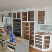 Custom kitchen cabinets being installed with new appliances in a bright, open-concept kitchen. Kitchen cabinet installation in progress for a modern home renovation.