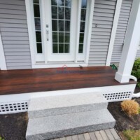 A beautifully renovated porch with fresh wood flooring and steps, showcasing expert construction and painting services. Professional porch renovation with new wood flooring and steps by Finish Masters Construction & Pain.