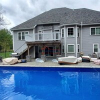 A completed residential house with a fresh paint job and a newly constructed deck, showcasing quality craftsmanship. Professional house painting and construction services at Finish Masters Construction & Painting.