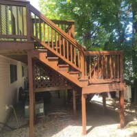 A newly built wooden deck with stairs and railing, showcasing professional craftsmanship by Finish Masters Construction & Painting. Wooden deck and staircase installation by Finish Masters. Expert construction and painting services.