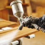 Skilled worker applying spray paint to wooden furniture for a smooth, professional finish at Finish Masters Construction & Painting. Professional spray painting of wooden furniture by Finish Masters Construction & Painting.