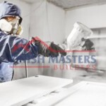 Skilled worker applying paint in a professional workshop setting. High-quality construction and painting services by Finish Masters. Professional construction and painting services by Finish Masters. Expert craftsmanship for resident.