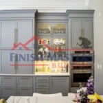 Elegant gray kitchen cabinets with built-in display and oven, showcasing professional construction and painting work. Custom gray kitchen cabinets with built-in display and oven, modern home renovation.