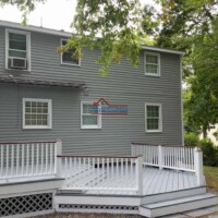 A freshly painted gray house with a white deck, showcasing expert exterior painting services by Finish Masters Construction & Painting. Professional exterior house painting by Finish Masters Construction & Painting.