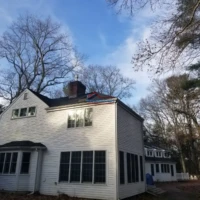 House with new siding and roof repair in progress.
