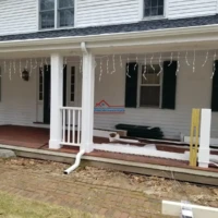 Exterior house painting and construction work on a porch with holiday lights.