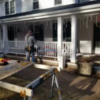 Professional worker installing new porch railing on a house exterior.