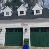 Garage door installation with dormer windows and exterior lighting.