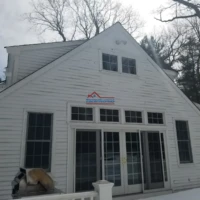 Exterior view of a white house being painted by Finish Masters Construction & Painting.