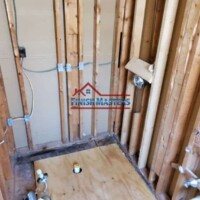 Framing and plumbing setup in a residential construction project by Finish Masters Construction & Painting. Interior wall framing and plumbing installation in a construction site.