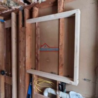 Construction workers framing a bathroom wall with wooden studs and plumbing pipes. Bathroom wall framing with wooden studs and plumbing rough-ins.
