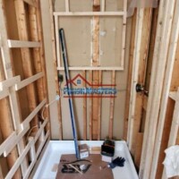 Interior bathroom construction with new shower base and wall framing in progress. Bathroom renovation with new shower base and wall framing.