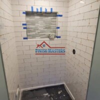 Professional interior wall tiling in progress at a construction site. Finish Masters specializes in construction and painting services. Interior wall tile installation by Finish Masters.