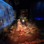 Recreated historical war scene with mannequins and vintage vehicle for educational display. Historical war scene with mannequins and vintage vehicle.