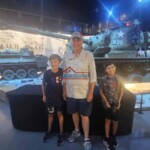 A family of three exploring a military tank display at a museum, enjoying their educational outing. Family visiting a military tank exhibit at a museum.