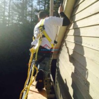 Skilled painter applying exterior paint to a house wall for a durable finish. Professional exterior house painting by Finish Masters Construction & Painting.