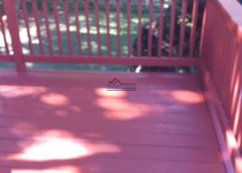 Professional deck staining and sealing service on a residential porch. Deck staining and sealing to protect and enhance outdoor wooden decks.