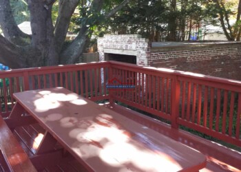 Beautifully built wooden deck with red stain and safety railing for outdoor enjoyment. Custom wooden deck with red stain and railing.