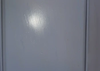 The details matter. Every imperfection revealed by primer is addressed and sanded smooth before the final finish is applied. Primed cabinet drawer front being inspected and sanded for a flawless finish