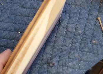 Precision repairs make all the difference. This damaged drawer front has been restored and blended seamlessly, ensuring the repair disappears beneath the final finish. Close-up of a repaired cabinet drawer front with seamless wood patching and profile restoration before refinishing
