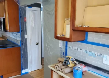 Attention to detail begins long before the paint is applied. Every surface is carefully protected to ensure a clean, professional cabinet refinishing project. Finish Masters cabinet painting preparation in Tewksbury Massachusetts showing wall cabinets, masking, and surface protection before sanding and refinishing.
