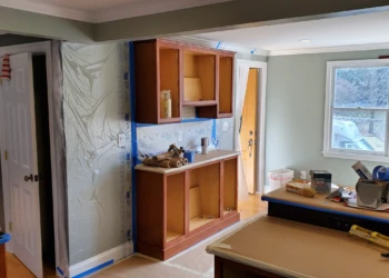 Proper masking protects more than the cabinets. Walls, doorways, and adjacent surfaces are sealed off to prevent dust and overspray from affecting the home. Finish Masters cabinet refinishing project in Tewksbury Massachusetts showing walls, doorways, and surrounding surfaces masked and protected from dust and overspray before sanding and painting.
