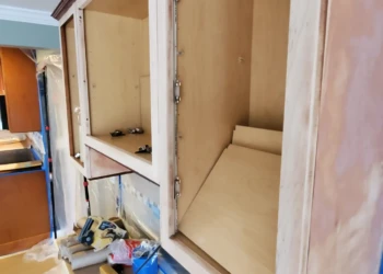 Installing new kitchen cabinets during home renovation project. Kitchen cabinet installation with open doors showing interior space.