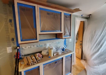 Professional results require professional containment. Dust barriers, masking, and surface protection are in place to ensure a clean application and a flawless factory-quality finish. Finish Masters cabinet refinishing project in Tewksbury Massachusetts showing cabinet boxes masked, dust barriers installed, and plastic containment sheeting in place before primer application.
