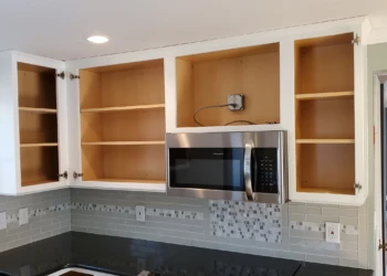 The transformation is nearly complete. With the cabinet boxes finished and all masking removed, the kitchen is now ready for the reinstallation of the doors and drawer fronts that will complete this better-than-factory cabinet refinishing project. Finish Masters cabinet refinishing project in Tewksbury Massachusetts showing completed upper cabinet boxes with masking removed and ready for cabinet door installation as part of our better-than-factory finishing process.
