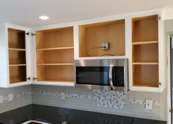 The transformation is nearly complete. With the cabinet boxes finished and all masking removed, the kitchen is now ready for the reinstallation of the doors and drawer fronts that will complete this better-than-factory cabinet refinishing project. Finish Masters cabinet refinishing project in Tewksbury Massachusetts showing completed upper cabinet boxes with masking removed and ready for cabinet door installation as part of our better-than-factory finishing process.
