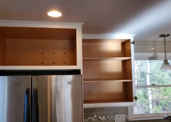 The upper cabinet boxes above the refrigerator have been fully refinished and are ready for reassembly. It's the culmination of a process built on preparation, craftsmanship, and accountability—not shortcuts. Finish Masters cabinet refinishing project in Tewksbury Massachusetts showing completed upper cabinets above the refrigerator ready for door installation and final reassembly.