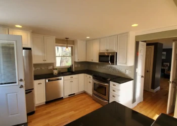 From every angle, the difference is clear. Professional preparation, premium coatings, and uncompromising craftsmanship combine to create a finish that Finish Masters is proud to stand behind with our name, reputation, and written warranty. Finish Masters cabinet refinishing project in Tewksbury Massachusetts showing an angled view of the completed kitchen featuring professionally refinished cabinets and a better-than-factory finish.