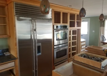 Kitchen cabinets being refinished with new paint and hardware.
