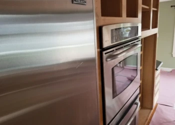 Kitchen cabinet refinishing with stainless steel appliances and wooden cabinetry.