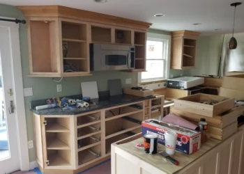 Kitchen cabinets being refinished with new paint and hardware.