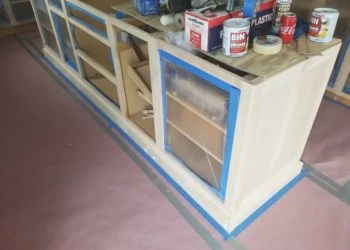 Cabinet refinishing in progress with masking and sanding tools visible.