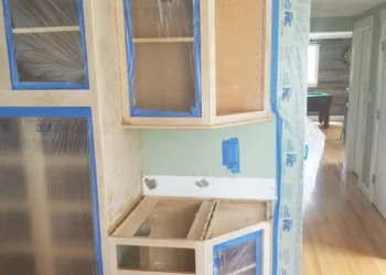 Cabinet refinishing process with masking and sanding in progress.