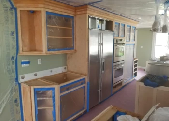 Kitchen cabinets being refinished with new paint and hardware.