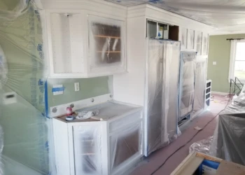 Kitchen cabinets being refinished, covered with plastic for protection.