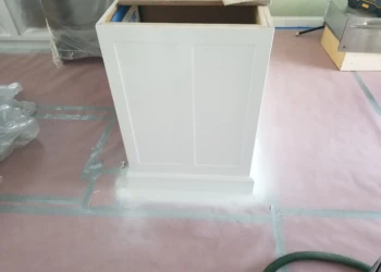 White cabinet being refinished with paint in a workshop setting.